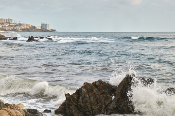 Fototapeta na wymiar Strong waves in the sea hitting the rocks of the coast