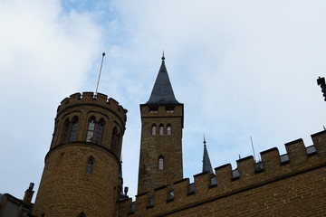 Hohenzollern castle with a tree partially covering the building of the castle on the background of blue sky with some white clouds. Bisingen Germany