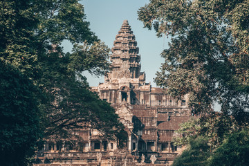 Angkor Wat - Hindu temple complex in Cambodia, largest religious monument in the world. Popular tourist attraction. View on the tower through the forest. - obrazy, fototapety, plakaty