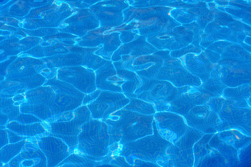 Fototapeta na wymiar Water surface with light reflections in a swimming pool as a background