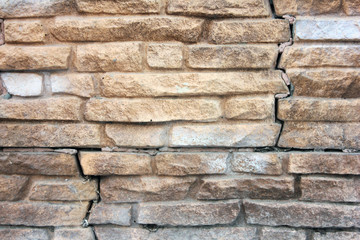 The background of the cracked brick wall in light orange or brown tone. Close up of old brick wall vintage texture with fissure.