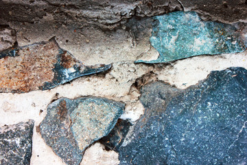 Wall of a building made of granite stones. Close up of stony old wall texture, natural rocks inside concrete wall.