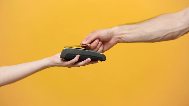Close up cropped photo of female holding in hands wireless modern bank payment terminal to process acquire credit card payments black card isolated on yellow background. Copy space mock up advertising