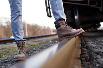 Girl in boots walks through the railroad tracks in autumn