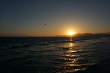 Sun going down behind a surfer and Paraglider off the beaches of Santa Monica, California