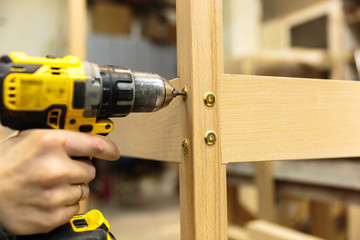 Building master with drilling machine. Professional carpenter working with wood and building tools in house.