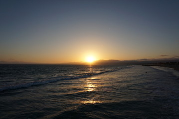 Sun going down behind a surfer and Paraglider off the beaches of Santa Monica, California
