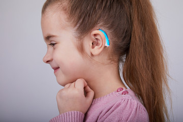  Hearing Aid in Young Girl's Ear. Toddler girl wearing a hearing aid. Studio shot