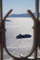 Fototapeta premium Cruise ship passing by the mountain side of Santorini, Greece in the open ocean