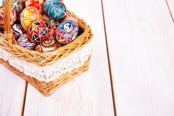 Easter eggs in a basket on white plank background.