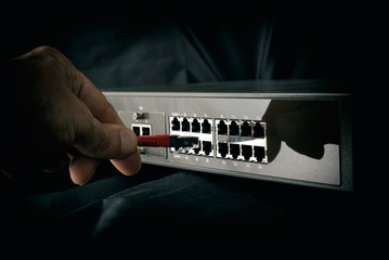 Technician plugging cable in switch - hub