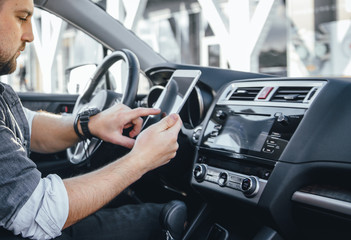 Young handsome driver man with smartphone serfing internet and drink black coffee