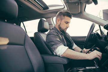 Young handsome driver man with smartphone serfing internet and drink black coffee