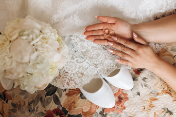 Wedding rings on the bride's hand is over the wedding dress and bouquet