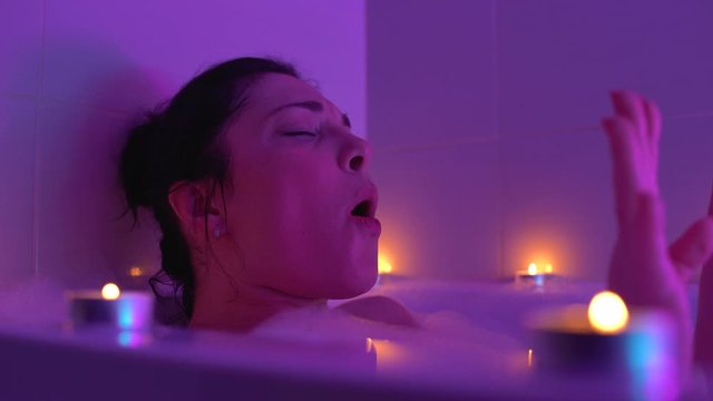 Happy woman enjoying music and singing in romantic bathroom atmosphere, relax