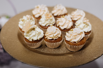 Tasty chocolate cupcakes with whipped cream on the golden plate