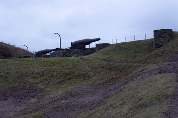 Fototapeta premium Old cast-iron artillery Russian cannon, old granite fortifications of the island-fort Suomenlinna overgrown with grass, Suomenlinna, gloomy autumn day in Finland.