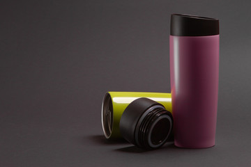 two multi-colored thermal bottles of shaker for sports nutrition on a black background.