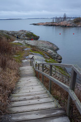 A road along a rocky shore and ancient historical stone fortifications overgrown with grass on the...