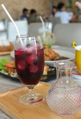 circle flower petals decoration with ice in wine glass. Red violet fresh juice cocktail