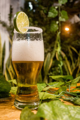 Delicious michelada type beer, on wooden table with night lights