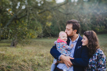 Young happy caucasian couple with little baby girl. Parents and daughter walking and having fun together. Mother and father play with child outdoors. Family, parenthood, childhood, happiness concept.