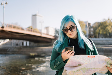 Fototapeta premium Tourist girl with blue hair looking at phone