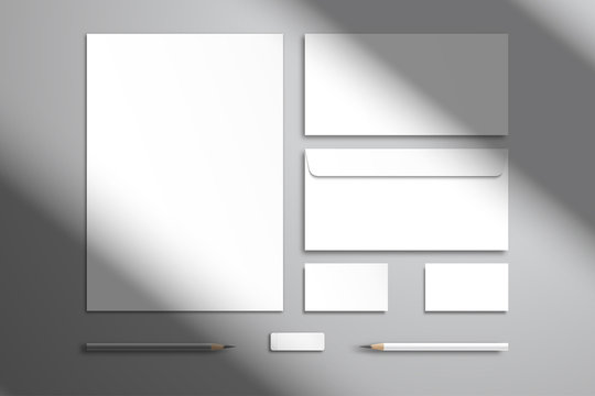 Flat layout with branding kit. White sheet of paper, two envelopes, two business cards, pencils and an eraser. Realistic template for design with shadow from the window
