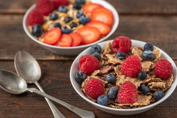 Granola chips with blueberries and raspberries in white bowl.