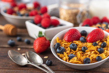 Healthy breakfast of cornflakes chips with blueberries and raspberries on dark desk.