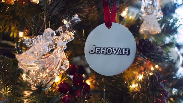 Slow dolly on "Jehovah" and glass angel ornaments hanging on Christmas tree