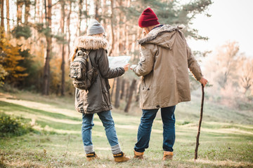 Travel couple with map, compass and backpack in the forest. Freedom and active travel concept.