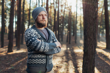 a young man with a beard walks in a pine forest. Portrait of a brutal bearded man Autumn forest
