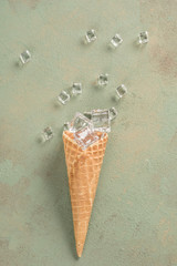 ice cubes in a ice cream cone on green background