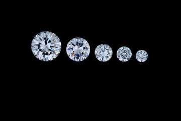 A row of five round faceted diamonds going from smallest to largest sits on a black background.
