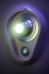 Reading lamp in a first class airline seat. Courtesy light in a plastic holder turned on with a switch visible.