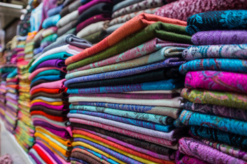 Piles of cotton and woolen Turkish blankets sold on the Grand Bazaar in Istanbul, Turkey. Colorful folded fabric sold in Grand Bazaar.