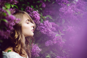 Beautiful young woman with closed eyes surrounded by lilac.