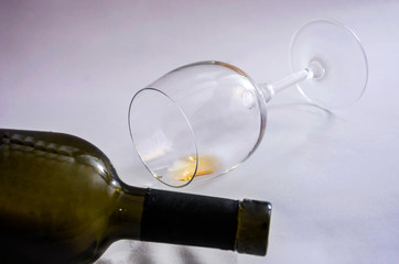 an inverted glass of wine, part of a discarded bottle. Close-up.