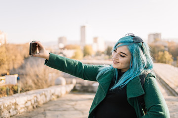 Obraz na płótnie Canvas Girl smiling and taking selfie using smartphone