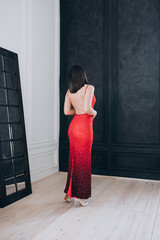 a woman in a red dress with an open back stands in front of the black and white walls