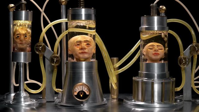 human heads without a body in cylindrical glass vessels (flasks), in a liquid with air supply (bubbles), similar to a laboratory for experiments, close-up