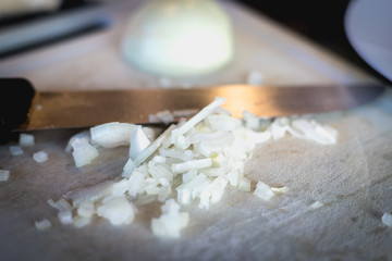woman cuts onions on a white plastic board
