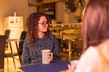 Girl having a cup of coffee having a conversation with a colleague.