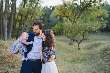 Young happy caucasian couple with little baby girl. Parents and daughter walking and having fun together. Mother and father play with child outdoors. Family, parenthood, childhood, happiness concept.