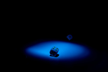 dice and chips on a black background illuminated by a small beam of light