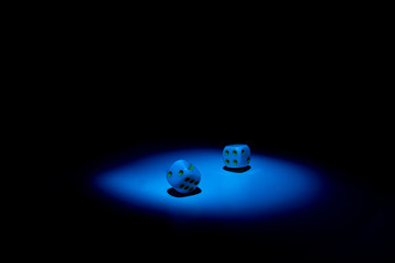 dice and chips on a black background illuminated by a small beam of light