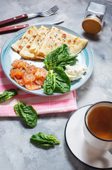Delicious breakfast - crepes with smoked salmon, spinach and sour cream on concrete background.