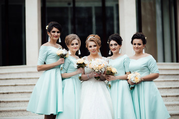 Bride and bridesmaids have fun and laughing during the wedding day posing on the stairs. Bride and...