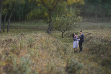 Young happy caucasian couple with little baby girl. Parents and daughter walking and having fun together. Mother and father play with child outdoors. Family, parenthood, childhood, happiness concept.